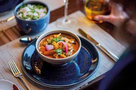 A person sitting in front of a curry on a table