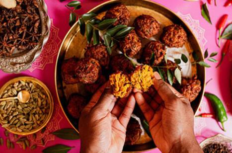 Two hands breaking food over a gold plate